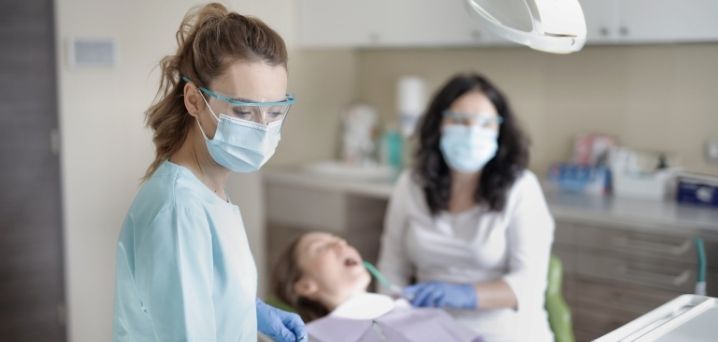 female dentist and nurse treating child patient