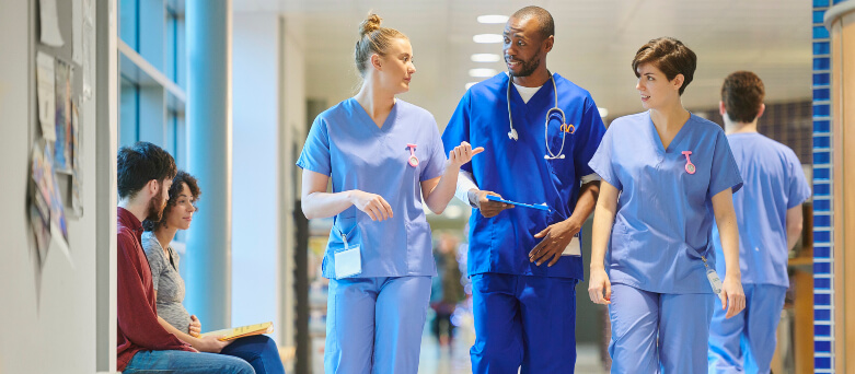 male and female nurses having discussion walking in hospital corridor