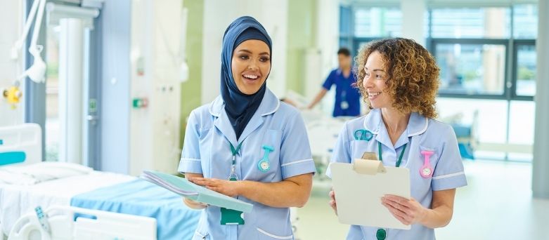 nurses talking whilst walking through a ward