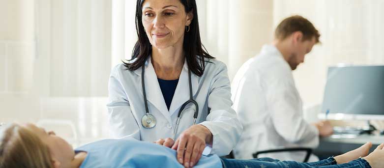 Female Gastroenterologist examining female patient by lightly compressing abdomen