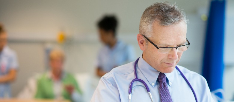 Female Medicine Doctor speaking to elderly female patient, making notes on tablet.